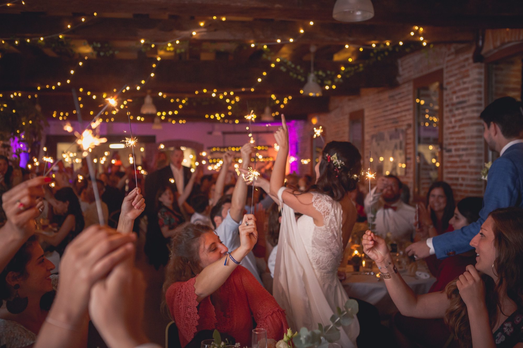 Interior wedding hall at Cellier du Val Boury with exposed beams, set up for a wedding dinner